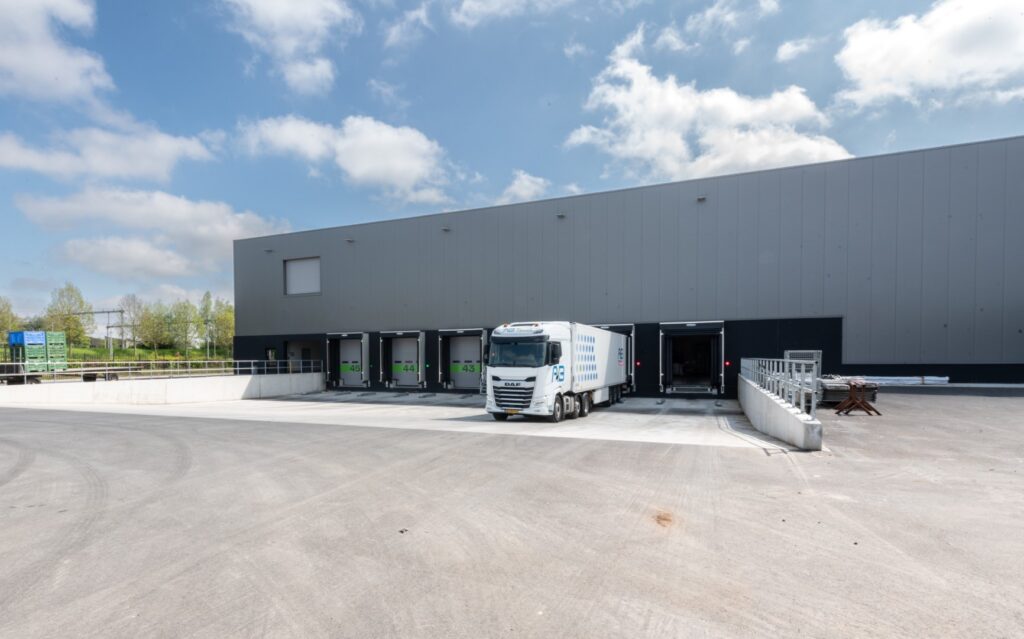 Moderne opslaghal met vrachtwagens en laadkades, geschikt voor bouwmaterialen en logistiek.