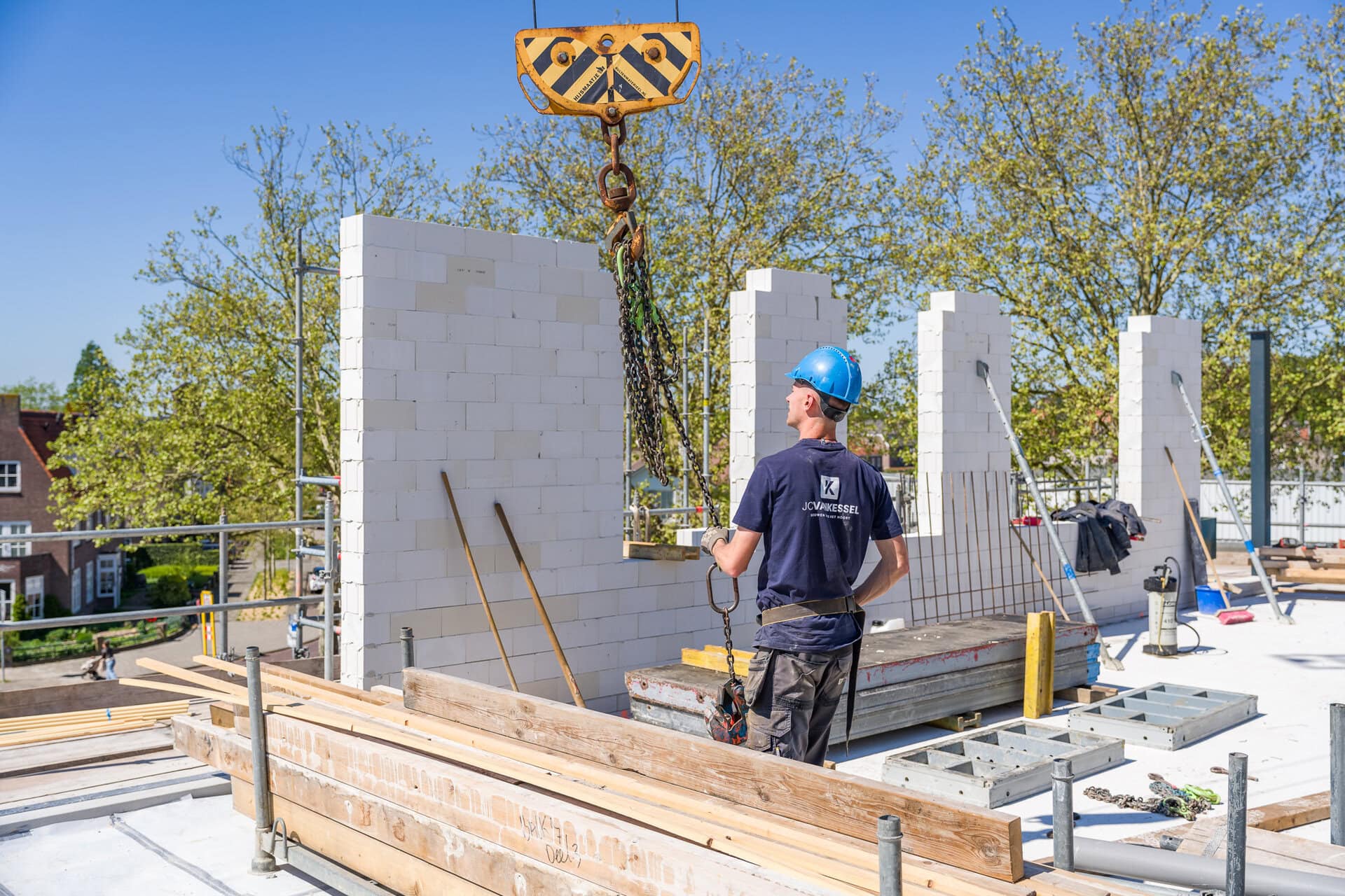 Arbeider plaatst bakstenen muur tijdens woningbouwproject.