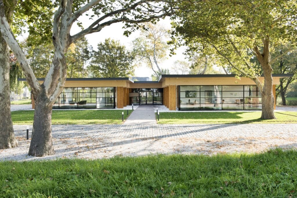 Moderne houten woning met grote ramen en omringend groen, perfect voor duurzame bouw.