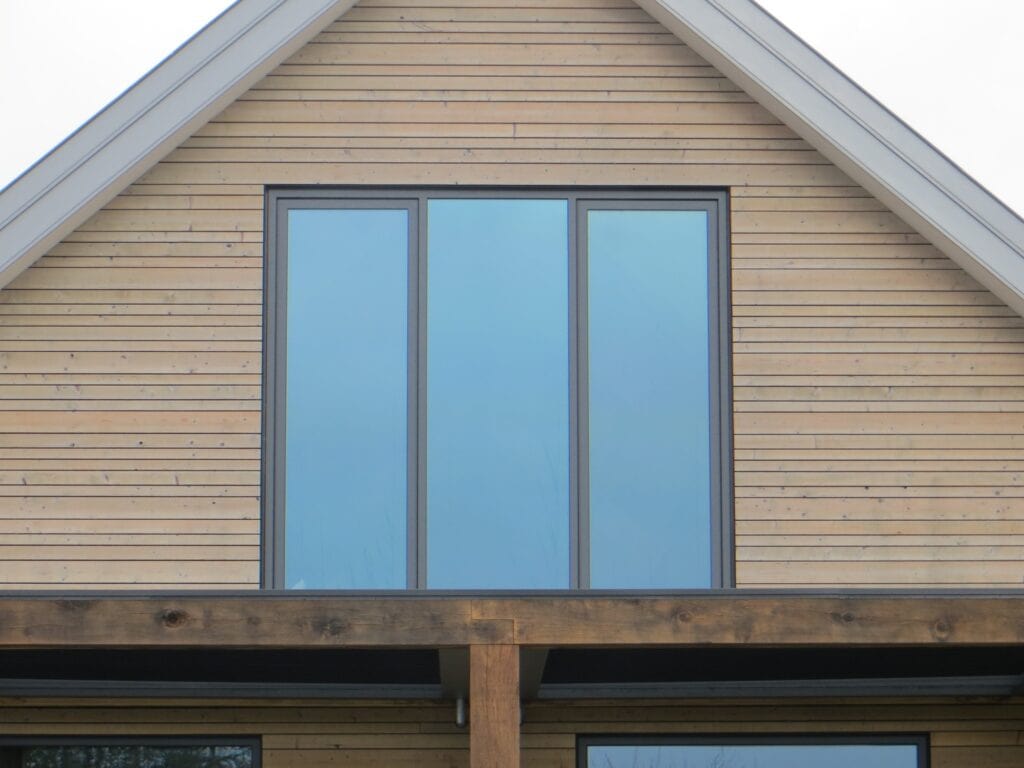 Houten woning met grote glazen ramen en moderne architectuur.
