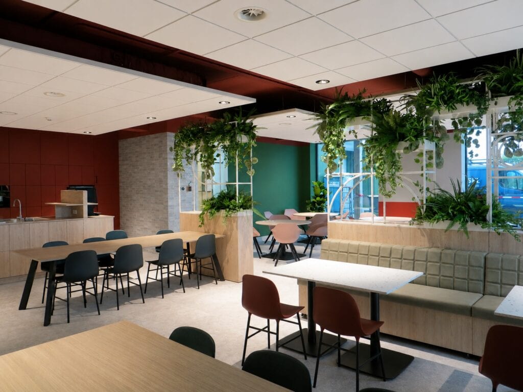 Moderne binnenruimte met planten, zitplaatsen en grote ramen voor natuurlijk licht.