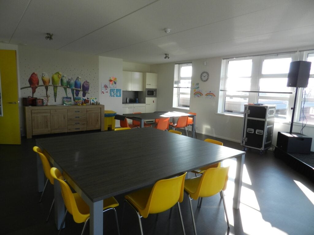 Speelruimte met kleurrijke decoraties en grote tafel voor kinderen.