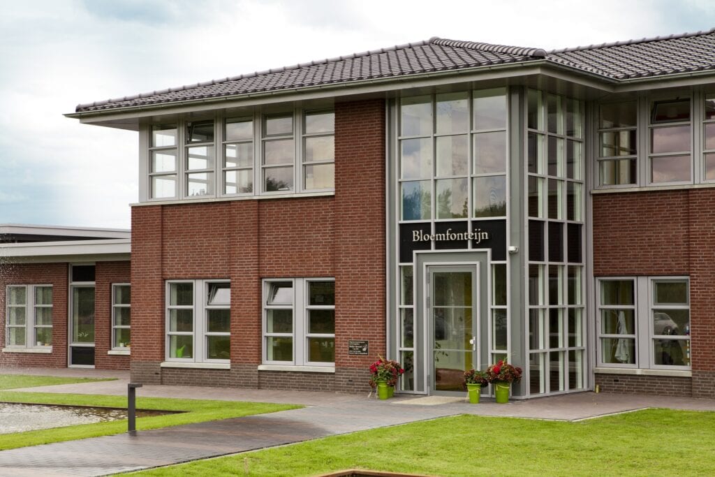 Modern kantoorgebouw van JCVANKESSEL BOUW met grote ramen en groene omgeving.