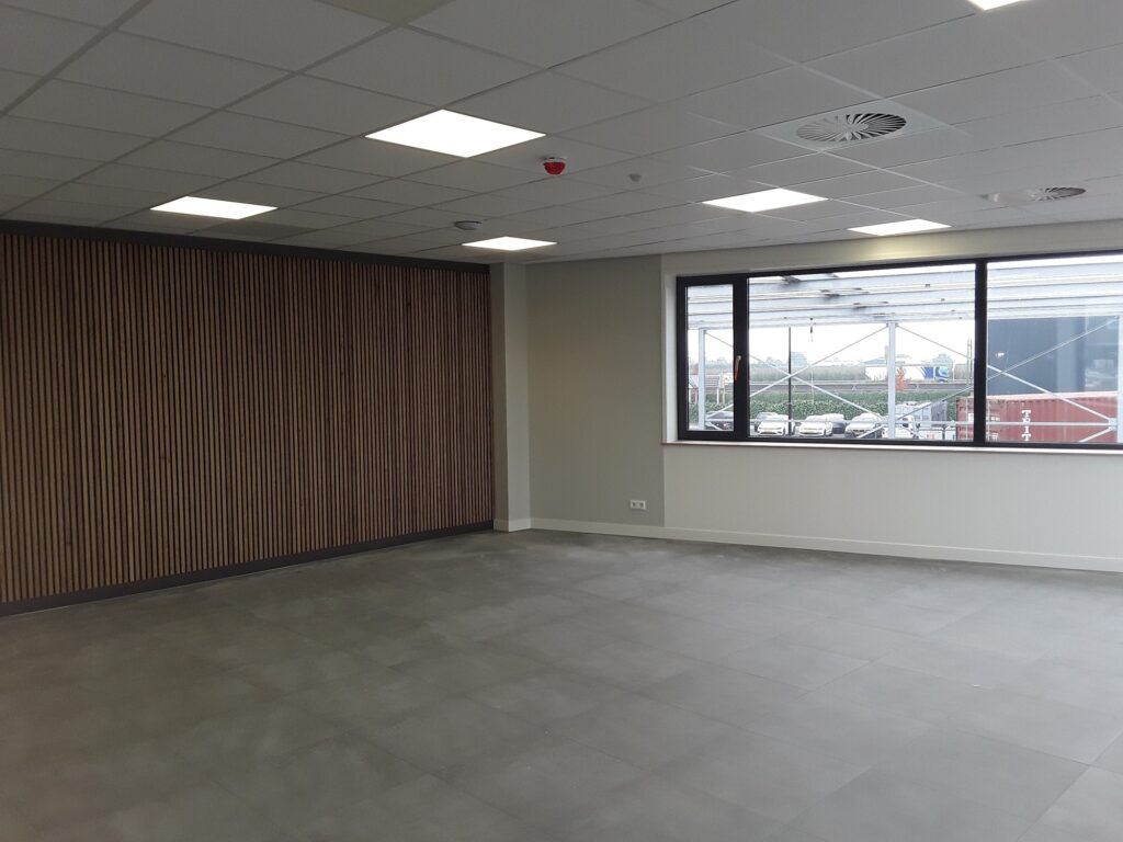 Nieuwe binnenruimte met grote ramen en houten wand door JCVANKESSEL BOUW.