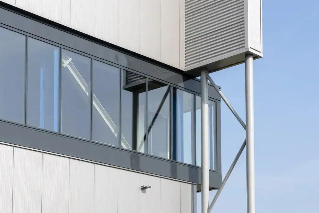 Moderne bedrijfsgevel met grote ramen en metalen steunpilaren.