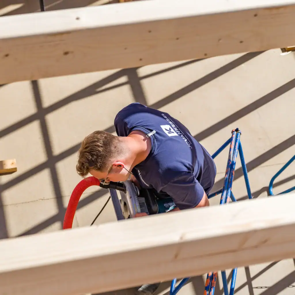 Bouwvakker werkt aan houten constructie op bouwplaats.