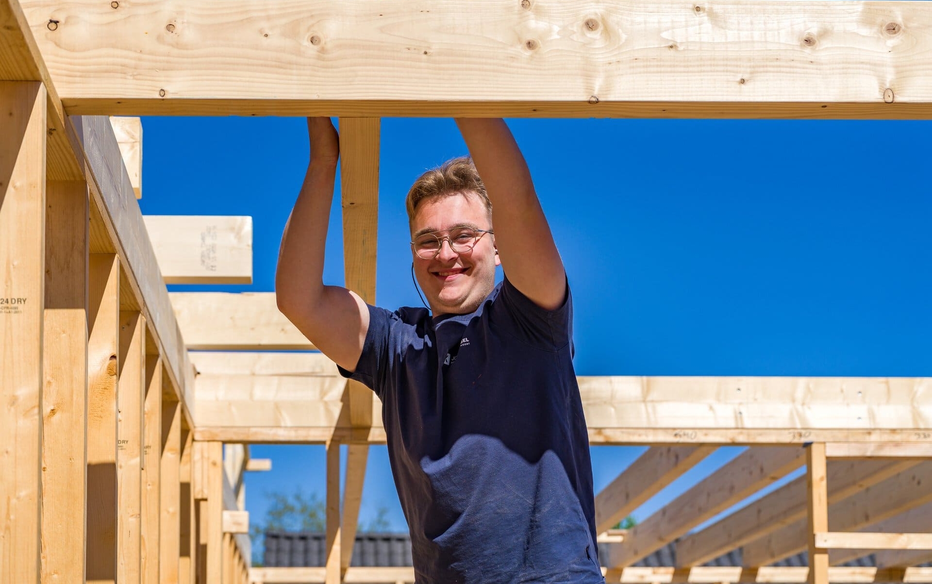 Mannen op een bouwplaats bevestigt houten balken aan een constructie in zonnige dagen.